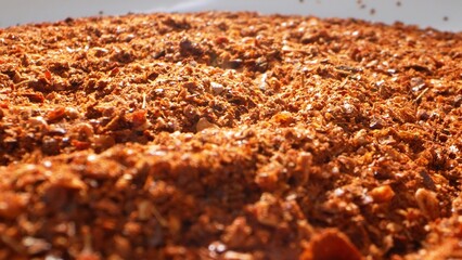 In the close-up, ground chili unveils its textured canvas: a blend of crushed flakes, tiny seeds, and fine powder, pulsating with a vivid red-orange hue, igniting taste buds with its fiery allure.
