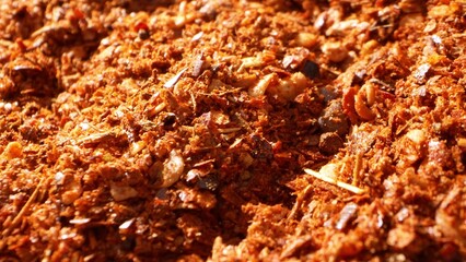Ground chili, a composite of crushed flakes, seeds, and powdered form, exhibits a coarse...