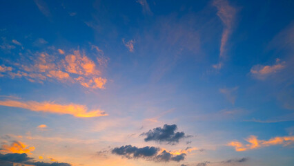 A beautiful sunset sky transitioning from deep blue at the top to softer, warm hues of orange and pink. Wispy clouds are illuminated by the setting sun, creating a serene and picturesque scene.
