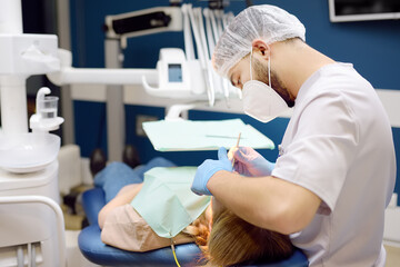 Dentist and patient at modern medical center. Doctor treats a young woman teeth in hospital....