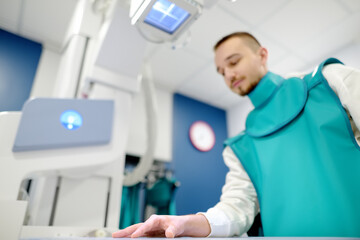 Young man having x-ray shot of broken hand in x-ray room in modern clinic. Patient wearing in...