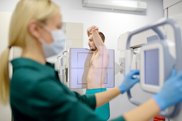 Female radiologist is making an Xray of lungs of patient in X-ray room of modern clinic. Doctor...