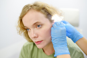 A patient is seen by an otolaryngologist. A professional ENT doctor examines a patient. An...