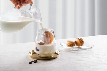 얼린 커피가 담긴  유리잔에 우유를 붓고 있습니다.
