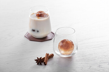 유리잔에 우유가 있고 커피를 얼린 둥근얼음이 있다.