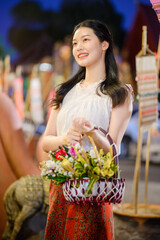beautiful Thai woman holding flower basket worship Chiang Mai City Pillar Inthakin Festival, crowd...