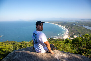 Adventurous climber hangs off Pedra do Telégrafo with breathtaking coastal view in Rio de Janeiro