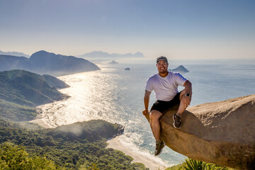 Fototapeta premium Adventurous climber hangs off Pedra do Telégrafo with breathtaking coastal view in Rio de Janeiro