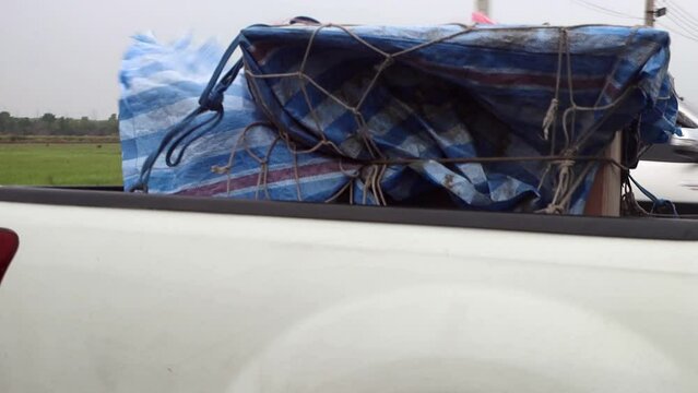 A pick up carries cargo covered by a tarpaulin