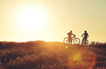 Sunset, people and friends in bicycle race with lens flare, exercise and adventure trail in nature...