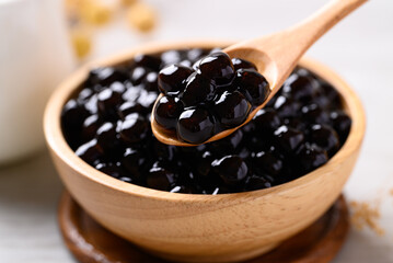 Black tapioca pearls or boba in wooden bowl with spoon, Ingredient in bubble tea