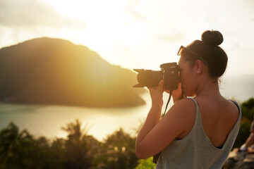 Sunset, photography and woman in nature shooting with camera, tech or memory of travel on island....