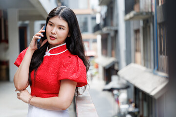 Asian girl talking on thje mobile phone standing in the city