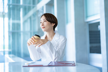 Obraz premium 休憩するカップを持つ白衣を着た女性