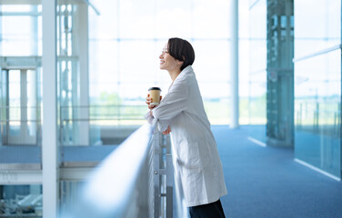 休憩するカップを持つ白衣を着た女性