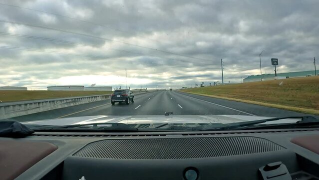 POV - Driving near Corpus Christi Texas on Interstate 37 on a cloudy day; refinery and large petroleum storage tanks along side the highway; concepts of energy, transportation and long haul