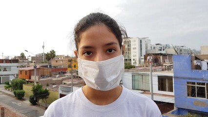 Girl, young woman in protective sterile medical mask on her face looking at camera outdoors. Air