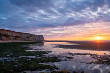 Obraz premium This lovely coastal sunset display features stunning cliffs, tide pools, and a sky painted with vivid colors