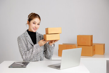 Asian smart entrepreneur business woman in casual suit surround by parcel boxes using computer...