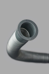 close-up of corrugated flexible pipe or hose, plastic or pvc flexi pipe joint isolated gray background, used in plumbing system for water supply and drainage in selective focus