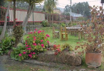 Fototapeta premium Garden with vibrant flowers and rustic wooden furniture.