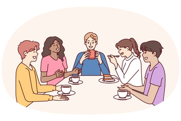 Group of multiethnic colleagues drink coffee sitting at table during break and laugh telling funny jokes. Happy people in casual wear relaxing enjoying socializing and meeting with school friends