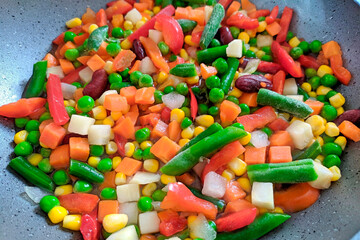 Vegetables frozen in pan for stew. Fresh vegetables food background - green beans, corn, red pepper, pea. Mixed frozen vegetables. Frozen cut veggie mix deep cool. Healthy vegetarian concept top view