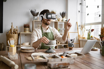 Man wearing VR headset sculpts clay vase in cozy pottery studio. Scene highlights fusion of...