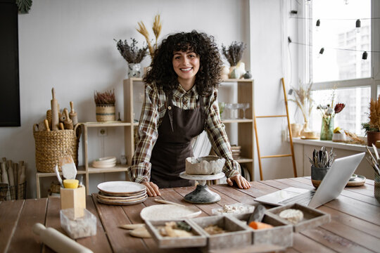 Smiling female potter working on a clay dish in a beautifully designed studio. Emphasizing creativity, craftsmanship, and artistic process.