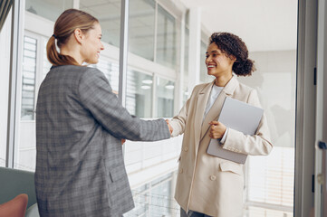 Happy young business woman manager handshaking greeting client in office