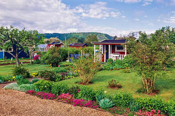 Idyllic little red cottage on an allotment garden with flowerbeds