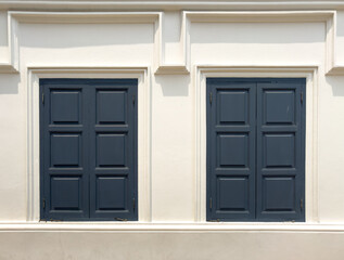 Closed wooden window on a white building wall