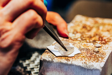 Close up of jewelers hands crafting two bezel earring settings