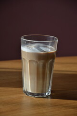 Poranna kawa w wysokiej szklance z pianką na drewnianym blacie