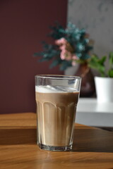 Poranna kawa w wysokiej szklance z pianką na drewnianym blacie