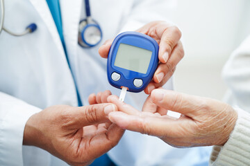 Asian doctor using digital glucose meter for check sample blood sugar level to treatment diabetes.