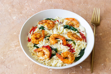 Orzo pasta with shrimp, spinach and tomatoes. Italian Cuisine. Seafood.