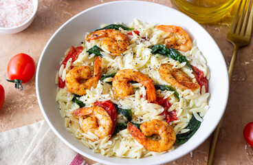 Orzo pasta with shrimp, spinach and tomatoes. Italian Cuisine. Seafood.