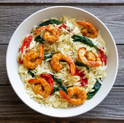 Orzo pasta with shrimp, spinach and tomatoes. Italian Cuisine. Seafood.