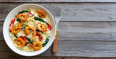 Orzo pasta with shrimp, spinach and tomatoes. Italian Cuisine. Seafood.