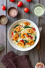 Orzo pasta with shrimp, spinach and tomatoes. Italian Cuisine. Seafood.