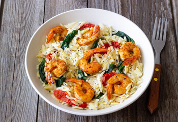 Orzo pasta with shrimp, spinach and tomatoes. Italian Cuisine. Seafood.