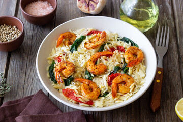 Orzo pasta with shrimp, spinach and tomatoes. Italian Cuisine. Seafood.