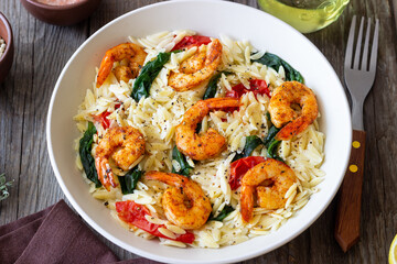 Orzo pasta with shrimp, spinach and tomatoes. Italian Cuisine. Seafood.