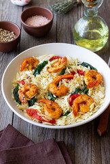 Orzo pasta with shrimp, spinach and tomatoes. Italian Cuisine. Seafood.