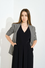 Studio portrait of a serious woman in a checkered jacket and a strict black dress