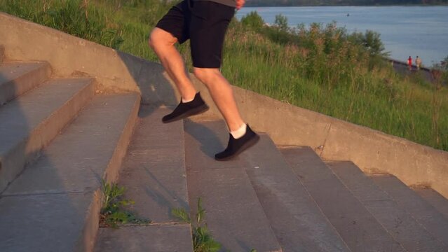 outdoor enthusiast runs along the concrete steps of the stairs, male sports person on an evening jog. fitness outside in the golden hour.