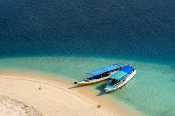 Fototapeta premium Boats by a sandy beach of 17 Islands National park, Flores Island, Indonesia