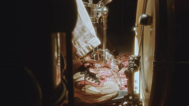 Foot of female drummer using pedal as playing bass drum during music performance on stage. Close-up view