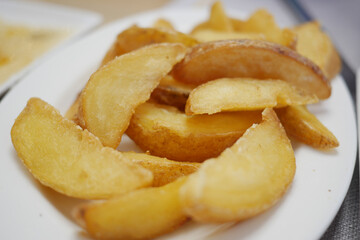 A mouthwatering closeup of delicious, crispy golden potato wedges served on a white plate